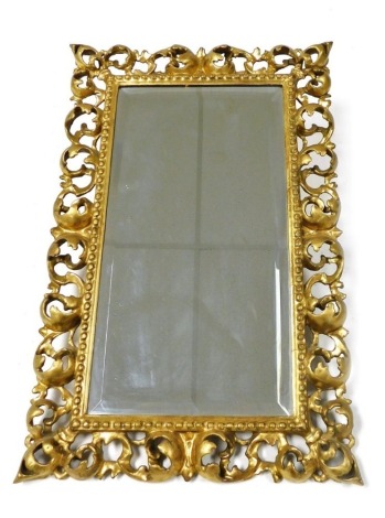 A 19thC Florentine gilt gesso wall mirror, of rectangular form, inset bevelled glass, within a pierced foliate scroll surround, 54cm x 35cm.