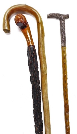 A carved rootwood walking stick, 87cm high, an early 20thC Anglo Indian walking cane, with a white metal handle embossed with scrolling leaves, 88cm high, and a further walking stick. (3)