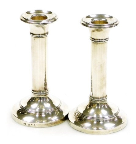 A pair of Edward VII silver candlesticks, of plain form with raised ribbed decoration, on a stepped, loaded base, Charles Boyton III, London 1902, 16cm high.