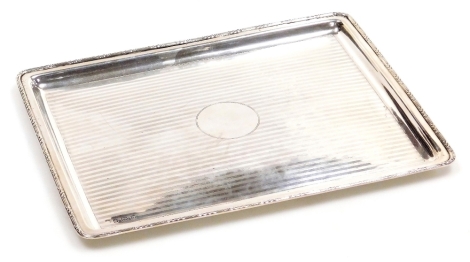 A George V silver tray, of rectangular form, with a leaf and raised line decorated border, engine turned decoration with circular vacant cartouche, Birmingham 1912, 15.72oz, 28cm x 22cm.