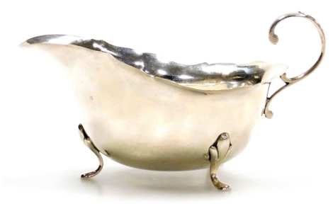 A George V silver gravy boat, with shaped rim and open handle, raised on three feet, William Suckling Ltd, Birmingham 1931, 2.83oz, 7cm high.