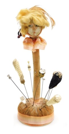 An early 20thC doll's head form hat pin holder, containing assorted hat pins, 30cm high.