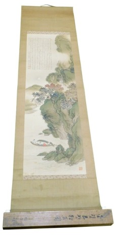 A Japanese Meiji period kakemono or scroll painting, of a river landscape with figures in a boat and lengthy inscription to the top left in Chinese style, with turned bone scroll ends, 212cm x 55cm, in original inscribed wood box.