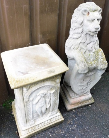 A concrete garden ornament, formed as a standing lion holding heraldic shield, on a separate plinth base carved with putti, 134cm overall.