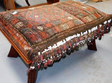 A 20thC camel seat, with a removable carpeted top with beaded tassels, on a carved hardwood base, 47cm high, 94cm wide, 60cm deep.