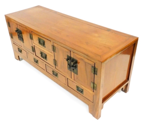 A Chinese elm sideboard, the top with two short drawers flanked by two cupboards, the base with four short drawers, with rectangular brass plates with shaped handles, on bracket feet, 58cm high, 139cm wide, 48cm deep.