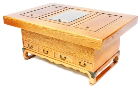 A Chinese elm hibachi coffee table, the top with three copper lined recesses, two with wooden covers the other with a glass cover, above an arrangement of drawers, the base with a moulded apron with brass capped bracket feet, 46cm high, the top 102cm x 70