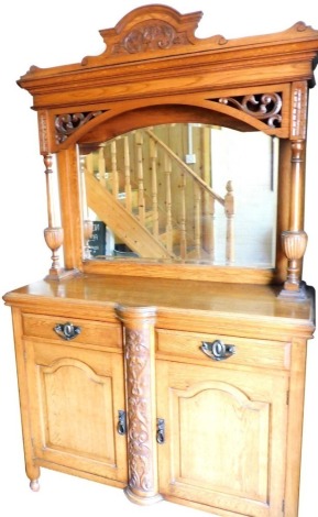 A Victorian oak mirror back sideboard, the arched pediment carved with leaves, above a bevelled glass mirror, behind a super structure with turned and fluted columns over two drawers above a pair of cupboard doors, raised on ball feet, 205cm high, 120cm w