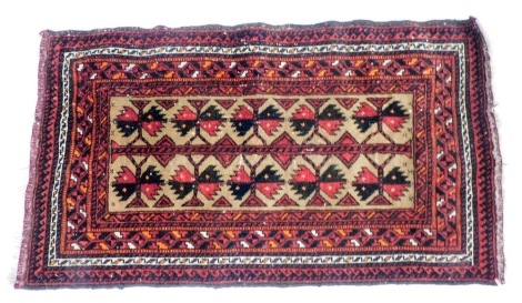 A Baluchi red ground rug, decorated with two rows of guls within repeating geometric borders, 46cm x 82cm.