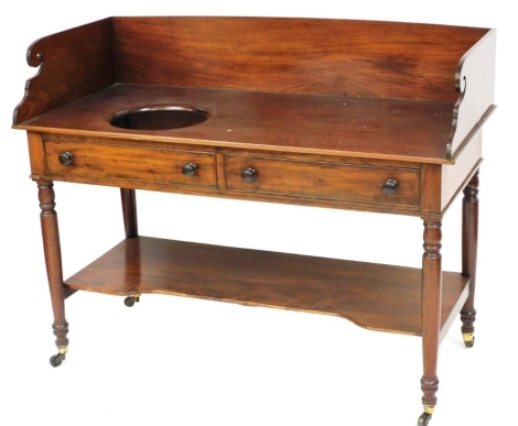 A Victorian mahogany wash stand, with a galleried top, with bowl recess, over two frieze drawers, raised on turned legs united by a shaped under tier, brass capped on castors, 100cm high, 130cm wide, 58cm deep.