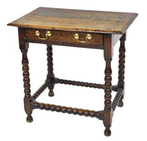 An 18thC oak side table, with a single frieze drawer, raised on bobbin turned legs united by a bobbin turned box stretcher, 72cm high, 75cm wide, 47cm deep.