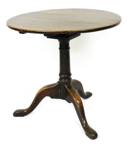 A Georgian oak tilt top occasional table, the circular top raised on a bird cage support and turned column over three cabriole legs, 68cm high, 71cm diameter.