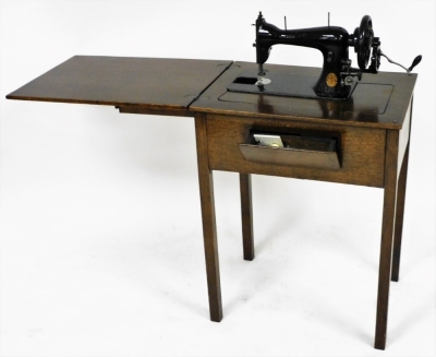 An oak sewing table, the hinged lid opening to reveal an interior with a Singer sewing machine, number S571190, raised on tapering square legs, 79cm high, 61cm wide, 43cm deep. - 2