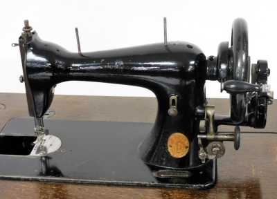 An oak sewing table, the hinged lid opening to reveal an interior with a Singer sewing machine, number S571190, raised on tapering square legs, 79cm high, 61cm wide, 43cm deep. - 3