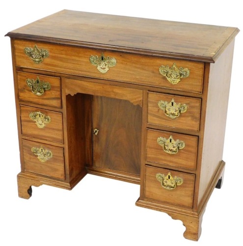 A Georgian mahogany kneehole desk, with one long frieze drawer, over a recess with semi secret drawer and cupboard below, flanked by six drawers, raised on bracket feet, 81cm high, 89cm wide, 51cm deep.