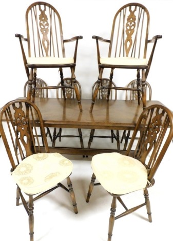 An elm refectory type table, the rectangular top with rounded edges, on trestle supports, and eight Windsor chairs, each with a pierced splat and solid seat on turned legs, two with arms, the table 74cm high 182cm wide, 80cm deep.