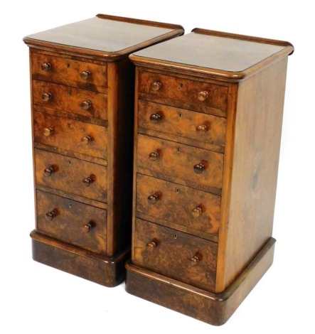 A pair of Victorian figured walnut pedestals, each with a raised back and moulded edge above five graduated drawers with turned wooden handles, on a plinth, 90cm high, 41cm wide, 48cm deep.