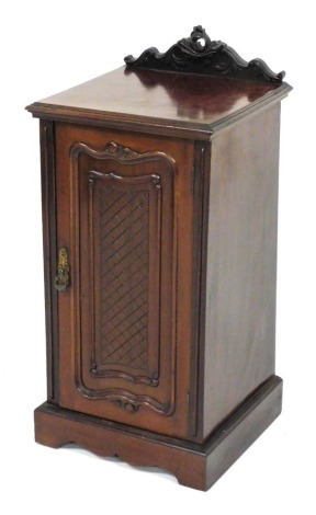 An Edwardian mahogany pot cupboard, with heavily carved cornice raised above a lattice panelled door, on bracket feet, 78cm high, 40cm wide, 38cm deep.