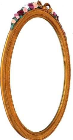 A Victorian barbola style gilt wood and painted oval wall mirror, with bow and floral surmount, 112cm high, 74cm wide.