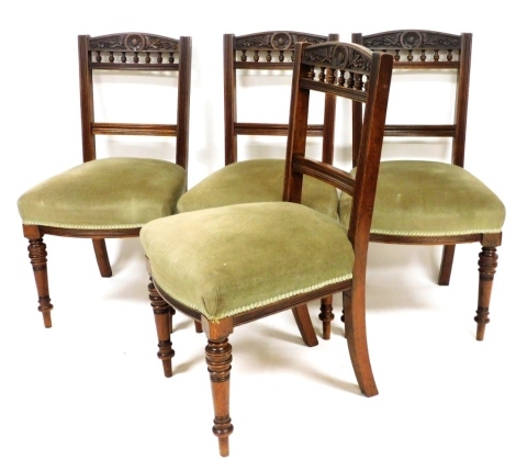 A set of four late Victorian walnut dining chairs, each with a spindle turned camel back, a padded seat on turned legs.