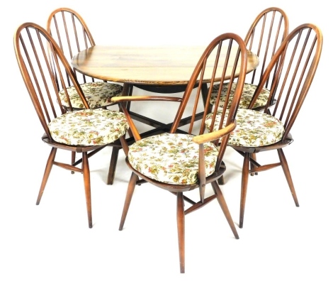 An Ercol dark elm and beech dining suite, comprising a drop leaf dining table, 71cm high, 112cm wide, 64cm deep, 122cm extended, and five dining chairs, model 2056, circa 1960, with loose cushion seats, comprising a carver and four single chairs.