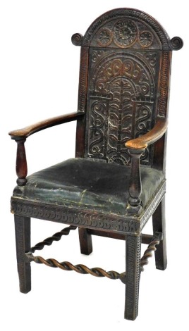 A 17thC oak and elm Wainscot chair, the back carved with a rose and two flower heads, above a tree of life and scrolling leaves, overstuffed green leather seat, raised on carved square legs, united by a barley twist stretcher, 55cm wide.