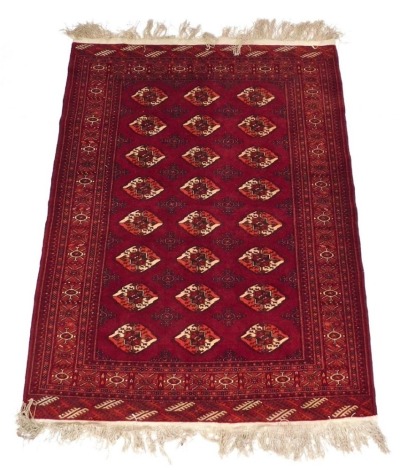 A Tekke red ground rug, decorated with three rows of eight guls within repeating floral and geometric borders, 143cm x 176cm.