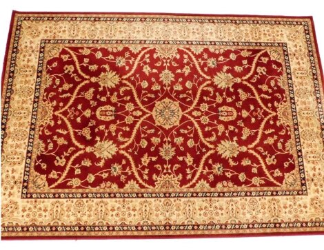 A Caucasian wool red ground rug, decorated centrally with floral motifs within multiple floral borders, 167cm x 226cm.