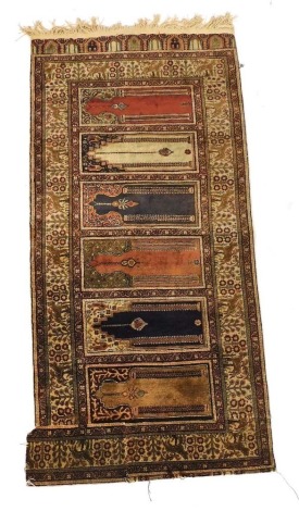 A Turkish prayer rug, decorated centrally with six Mihrabs within multiple animal and flora decorated borders, cut and with additional section added to border, 84cm x 174cm. (AF)