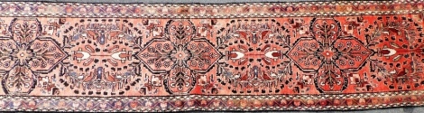 A Persian runner, on a washed red ground with floral medallion design, 365cm x 80cm.