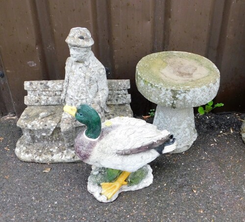 A composition garden ornament of a man on bench, 43cm high, a plastic duck ornament, 29cm high, and a composition garden plinth, 28cm high.