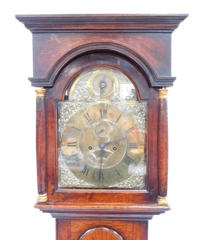 A George III longcase clock, with inset pillared hood, full length moulded trunk door and plain base, the square arch dial having silent/strike roundel to the arch, the chapter ring having Roman hour and Arabic minute numerals, enclosed by cast brass urn 