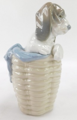 A Lladro figure of a dog in a basket, 17cm high. - 2