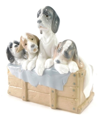 A Lladro figure group of four dogs in a basket, 21cm high.