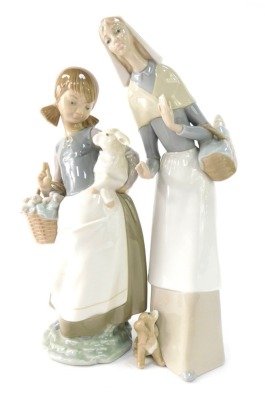 Two Lladro figures, comprising a girl carrying a lamb and a basket of flowers, 23cm high, and a lady with a puppy, 28cm high. (2)