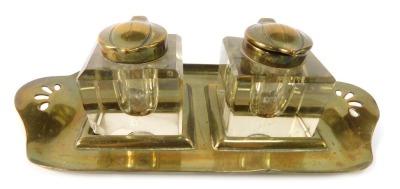 An Art Nouveau brass ink tray, with two cut glass ink wells, each with brass capped lid, 8cm high, 22cm wide.