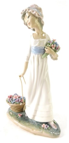 A Lladro porcelain figure group of a lady carrying basket of flowers, 28cm high.