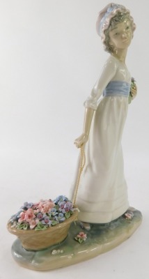 A Lladro porcelain figure group of a lady carrying basket of flowers, 28cm high. - 2