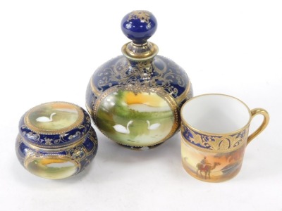 A Noritake trio set, on royal blue ground picked out in gilt, comprising coffee can, vase and cover with swans, 13cm high, and a trinket dish, (AF). (3) - 2