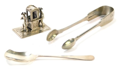 A small group of silver, comprising an Eastern white metal carriage ornament, a silver shovel spoon, 1 ½oz, and a pair of silver plated sugar tongs. (3)