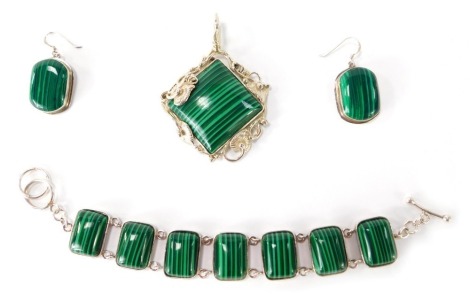 Three items of silver and malachite jewellery, comprising a bracelet set with six oblong malachite stones, 18cm long, a pair of drop earrings and a pendant with lily leaf scroll border, 6cm high, 69.1g all in. (3)