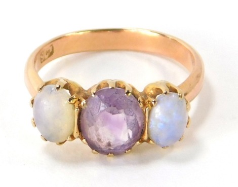 A 9ct gold amethyst and moonstone three stone dress ring, with three oval cut stones in claw setting, on a yellow metal band, stamped 9ct, size L ½, 2.4g all in.