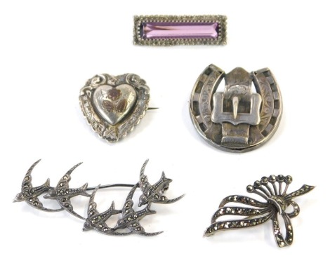 Five silver brooches, comprising two Victorian buckle brooches, a purple paste stone set bar brooch, a swallow marcasite brooch and a marcasite fan brooch, 25.2g all in. (5)