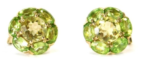 A pair of 9ct gold peridot cluster earrings, each cluster with central citrine surrounded by six oval cut peridots in claw setting, with clip clasp, the stud 1.2cm wide, 5.4g all in.