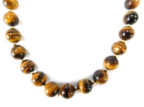 A tiger's eye necklace, with spherical tiger's eye beads, 10mm wide on a wire with 9ct gold ball breaks and clasp, 52cm long, 63.7g all in.