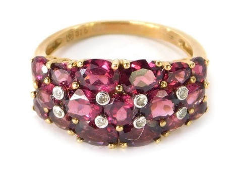 A 9ct gold dress ring, of half hoop design set with oval and round brilliant cut garnets, and eight tiny diamonds in rub over setting, ring size P½, 3.7g all in.