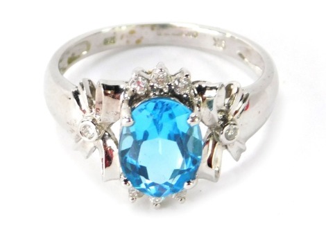 A 9ct white gold dress ring, with an oval cut aquamarine, and CZ set bow shoulders, stamped QVC, ring size Q, 3.6g all in.