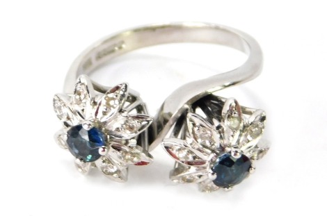 A 9ct white gold twist design cluster ring, with two floral points, set with semi-precious blue stone and CZ set petals, on raised basket with twist design, ring size M½, 5.5g all in.