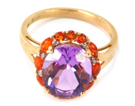 A 9ct gold cluster ring, with central oval amethyst in four claw setting, surrounded by orange semi precious stones and CZ stones, on V splayed shoulders, ring size P½, 3.7g all in.