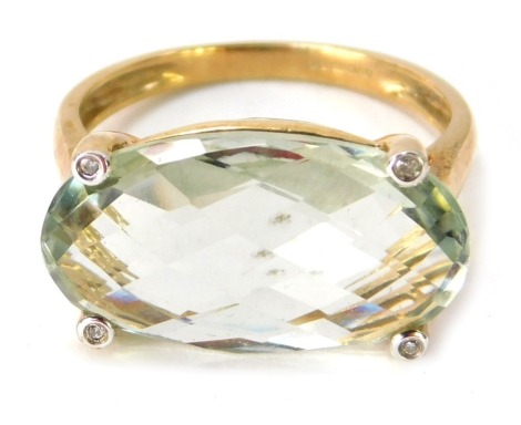 A 9ct gold semi precious stone set dress ring, the central oval pale green faceted stone with four outer point tiny diamonds borders, on a raised basket, ring size P½, 4.3g all in.